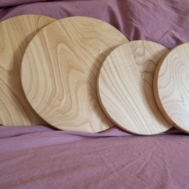 Four cake stand tops in two sizes against some purple fabric.