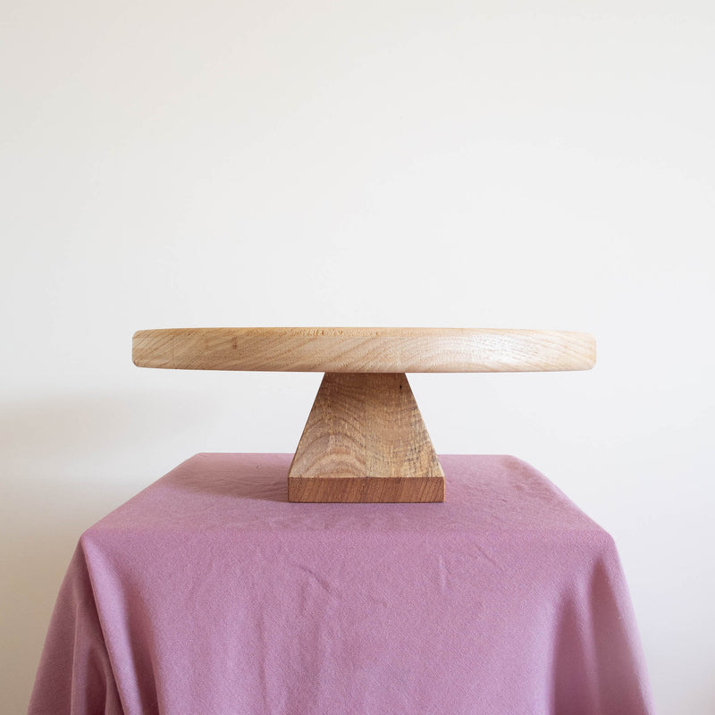 A stand made from oak, ash and sapele against an off-white wall on some purple fabric.