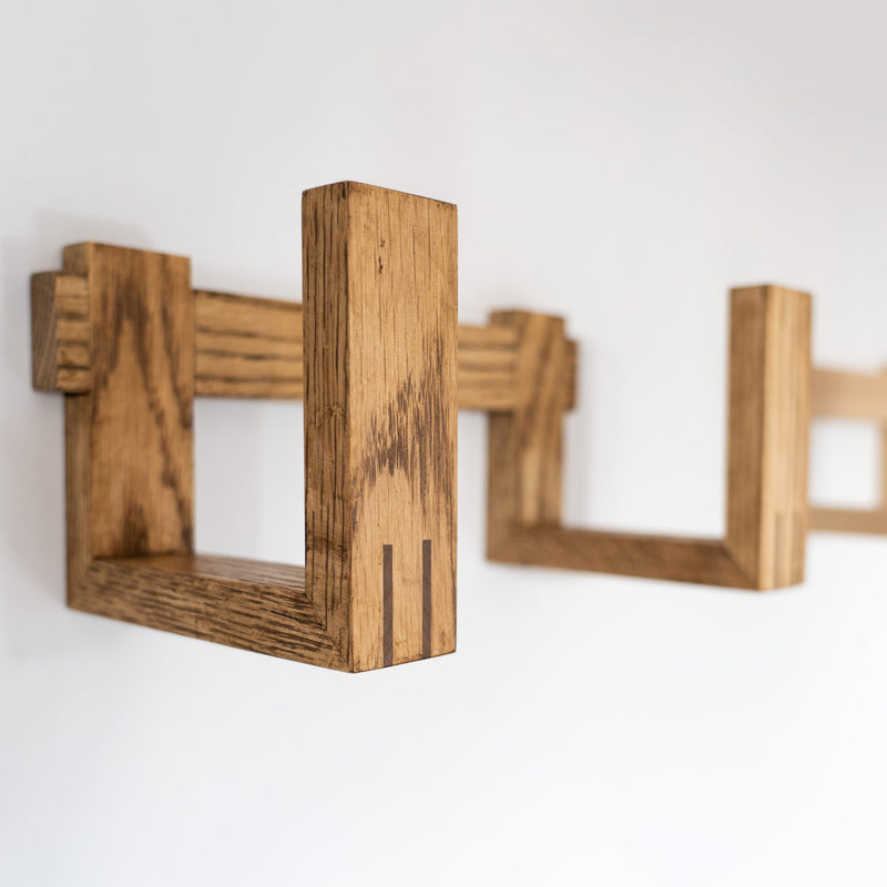 Side view of two oak record racks mounted to a white wall. Focus is on the rack finished in a dark hard wax oil with the lighter oak rack blurred in the background.