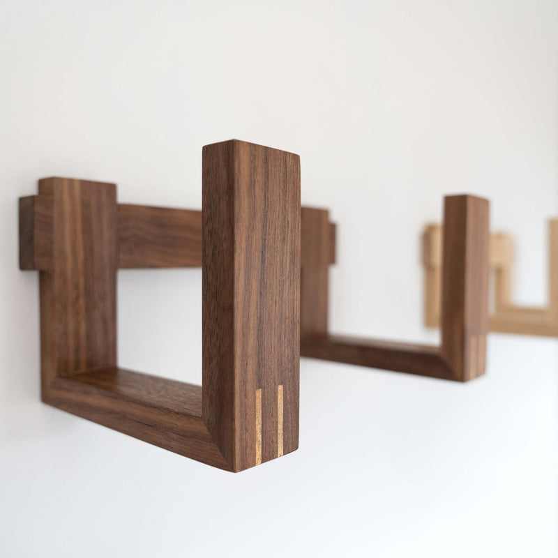 Singular walnut record rack finished in a clear hard wax oil mounted to a white wall. Focus is on the spline detail.