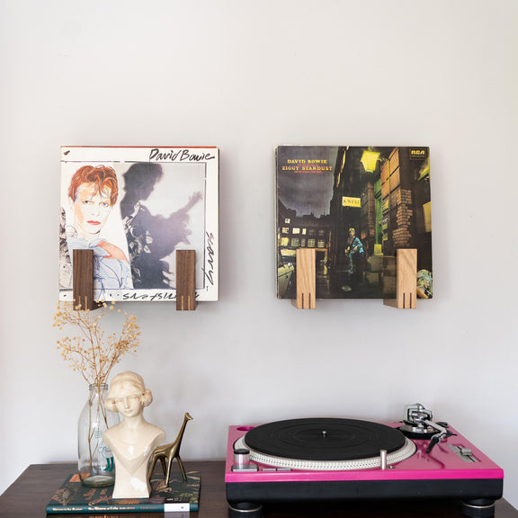 Front view of two record racks holding lots of albums. The rack on the left is made of walnut and the rack on the right is made from oak. Both racks feature David Bowie records at the front. A Technics record deck sits below the racks to the right.