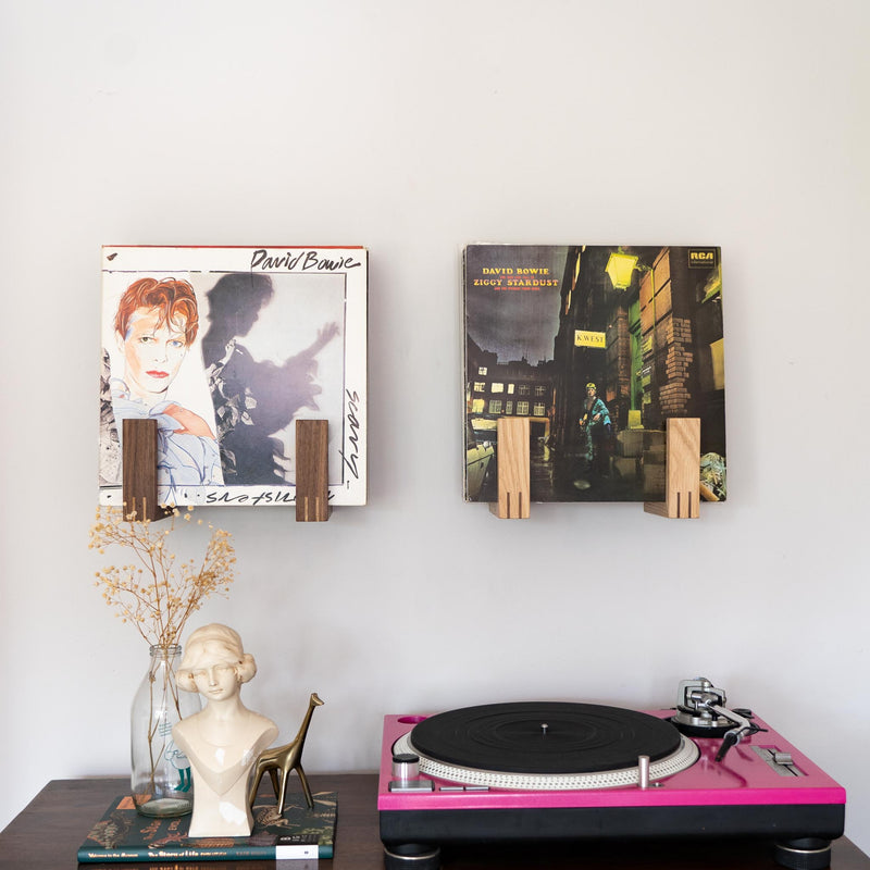 Front view of two record racks holding lots of albums. The rack on the left is made of walnut and the rack on the right is made from oak. Both racks feature David Bowie records at the front. A Technics record deck sits below the racks to the right.